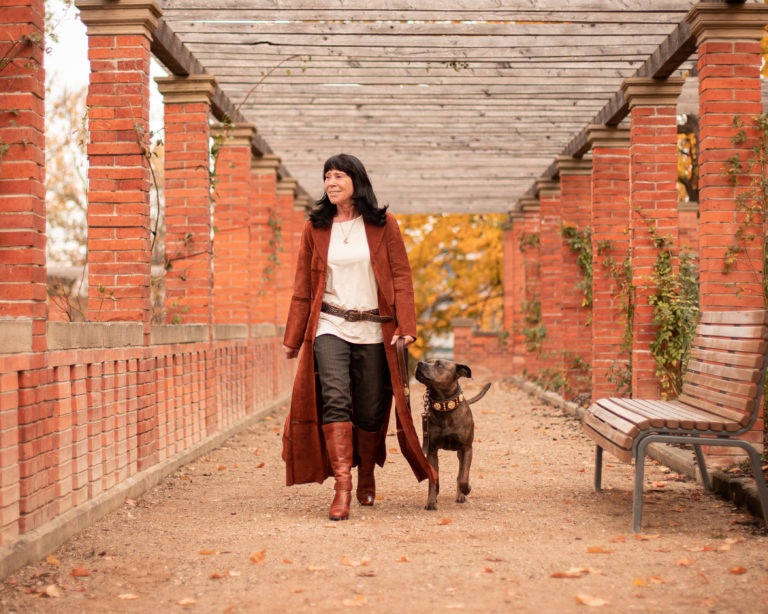Frau mit Hund an der Leine auf Ziegelmauer-Hintergrund