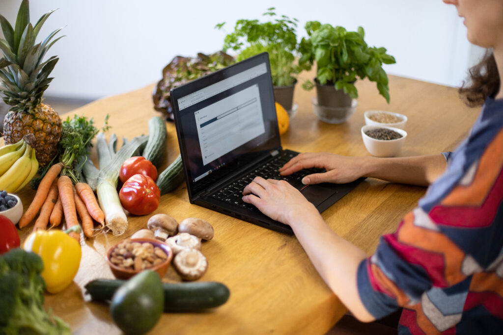 Laptop surrounded by veggies and healthy food